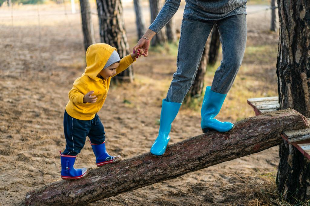 a mother helping a toddler balance on a log.