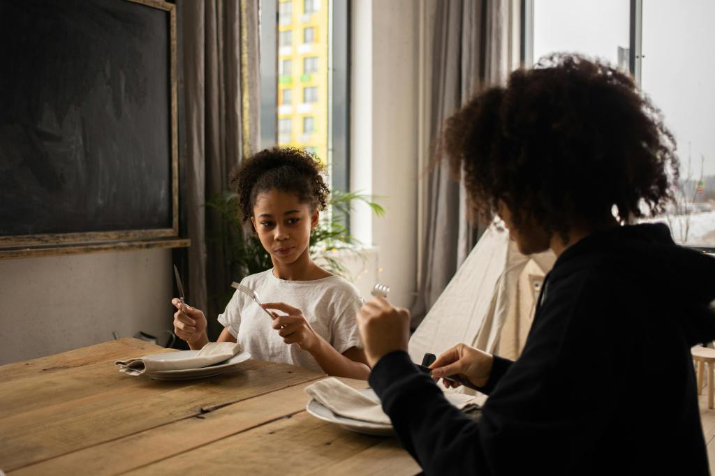 a mother teaching daughter good manners at the table.