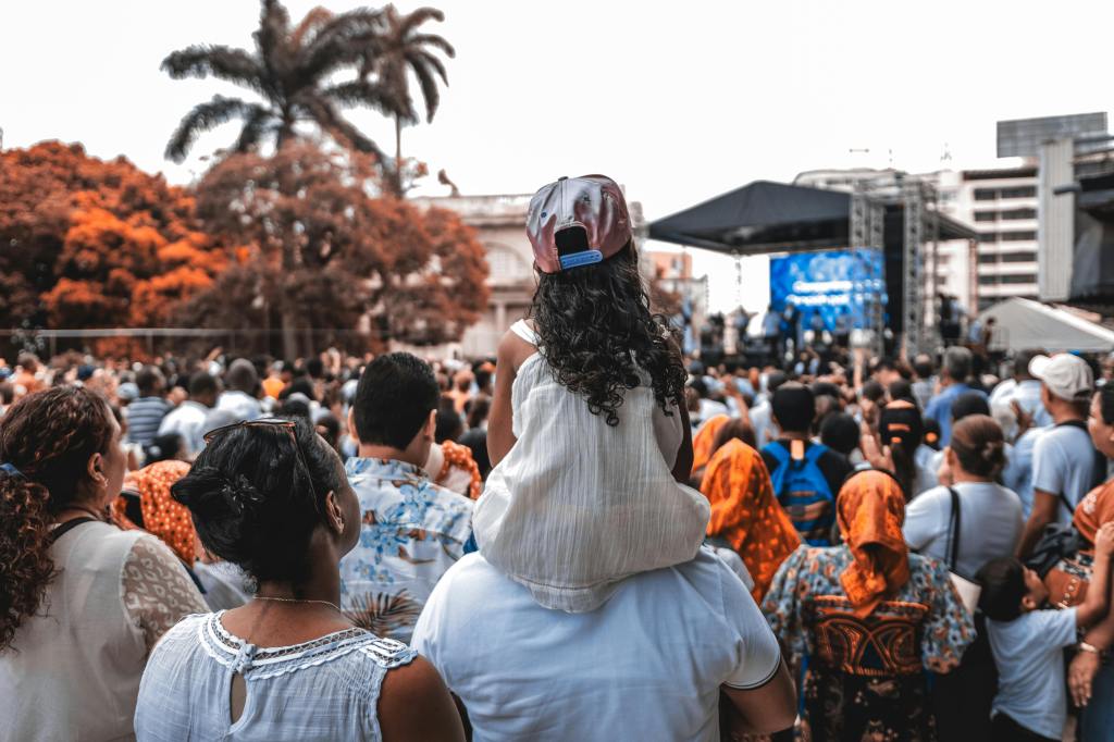 family at an outdoor concert with daughter sitting on fathers shoulders