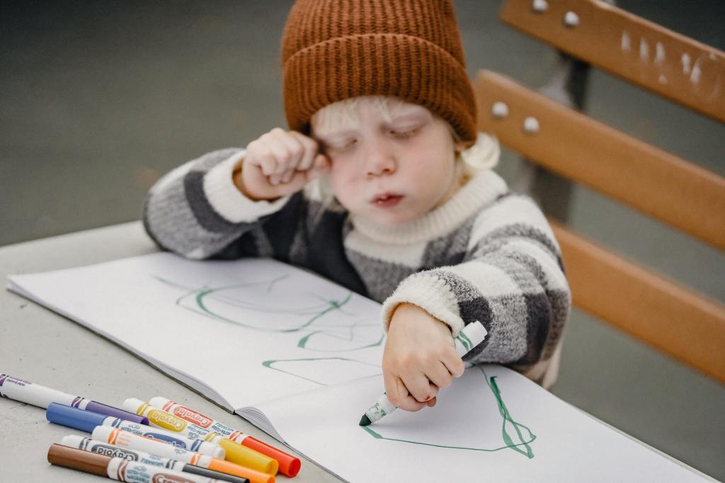 child creating a scrapbook by drawing pictures with markers