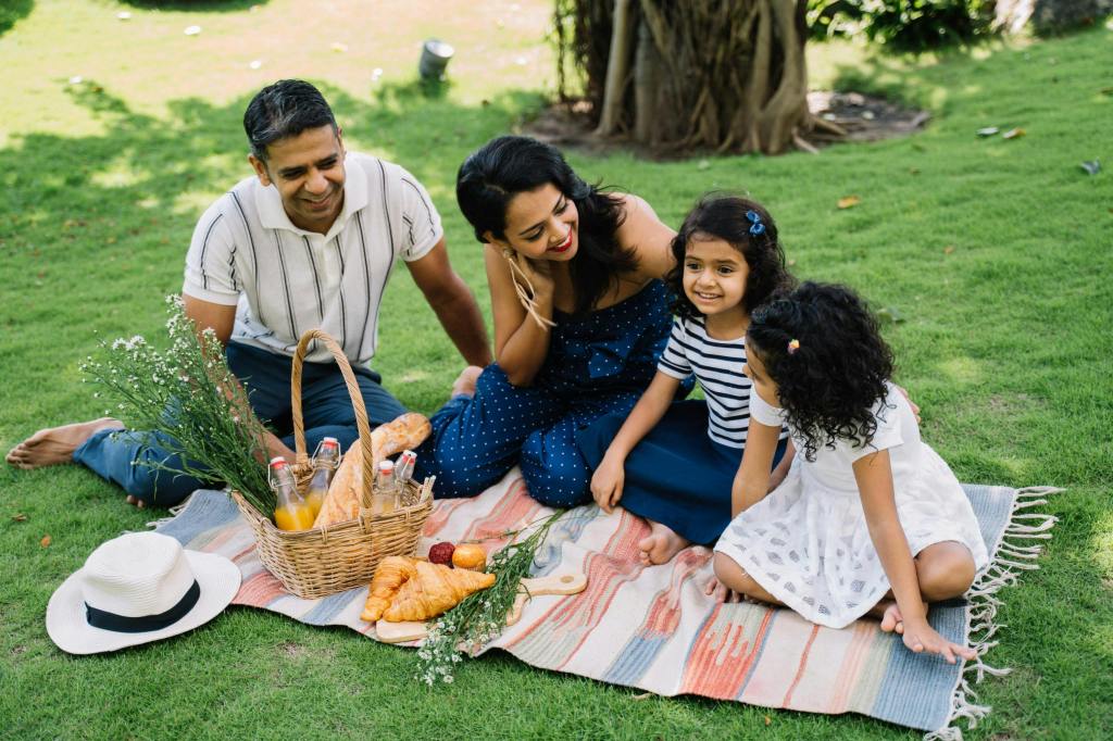 family of four with two daughters having a picnic on the grass
