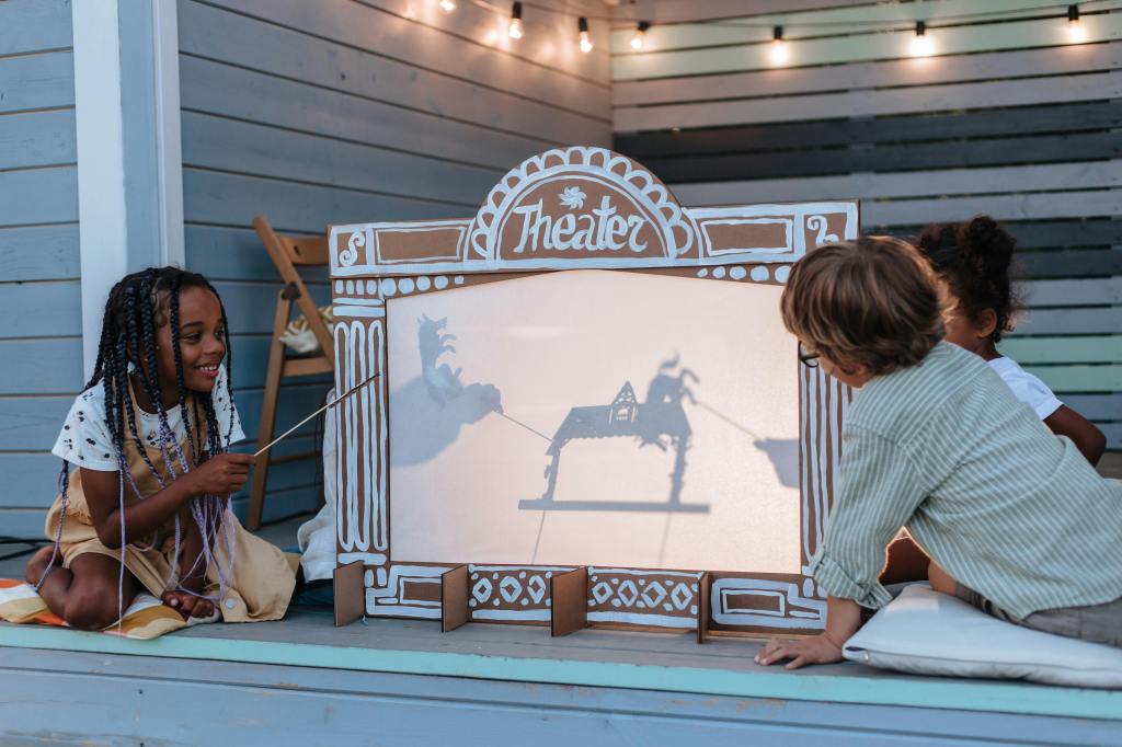 three kids having a puppet show on the porch