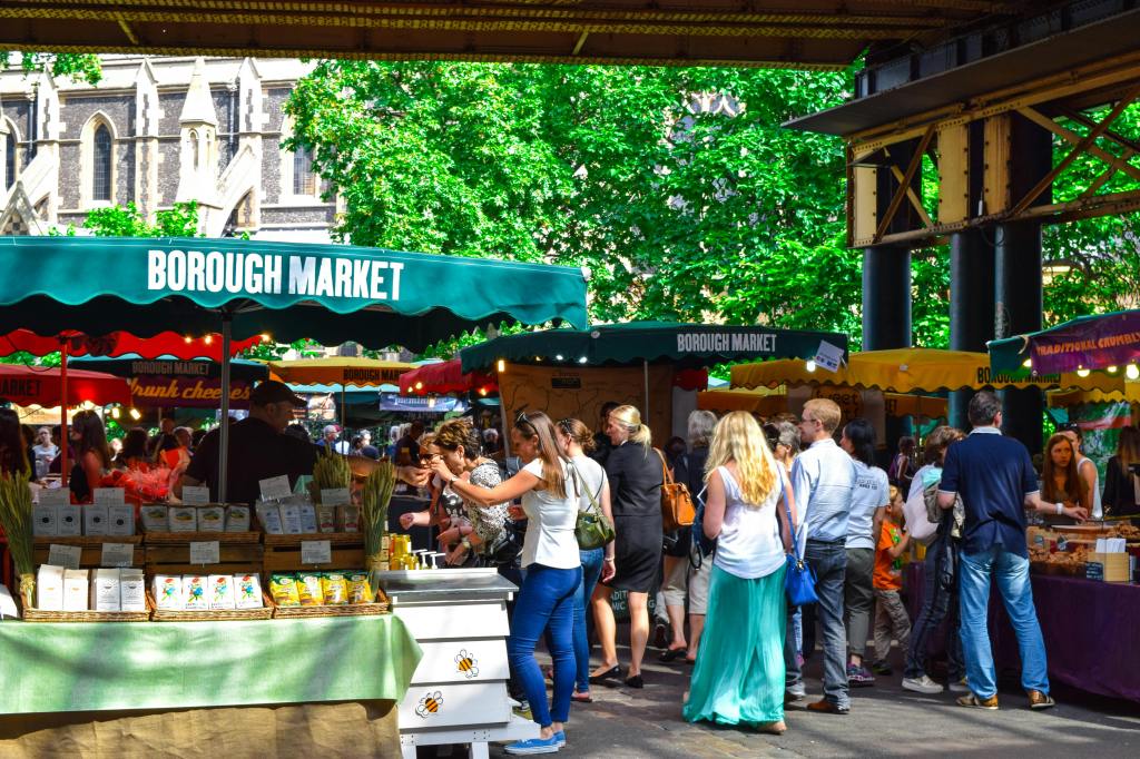 a farmers market with people picking fruit and vegetables